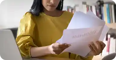 woman working on personal computer with a dslr camera next to her