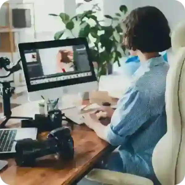 woman working on personal computer with a dslr camera next to her